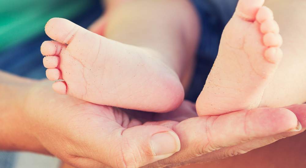 Newborn baby feet held gently in hands, symbolizing successful pregnancy through egg donation and IVF treatment Newborn baby feet held gently in hands, symbolizing successful pregnancy through egg donation and IVF treatment